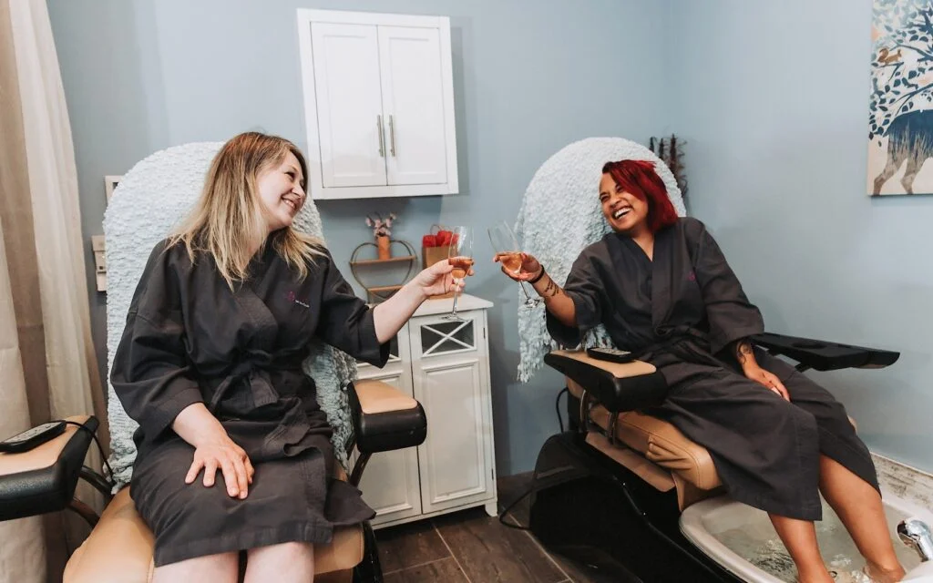 Two women cheers with champagne during a spa party